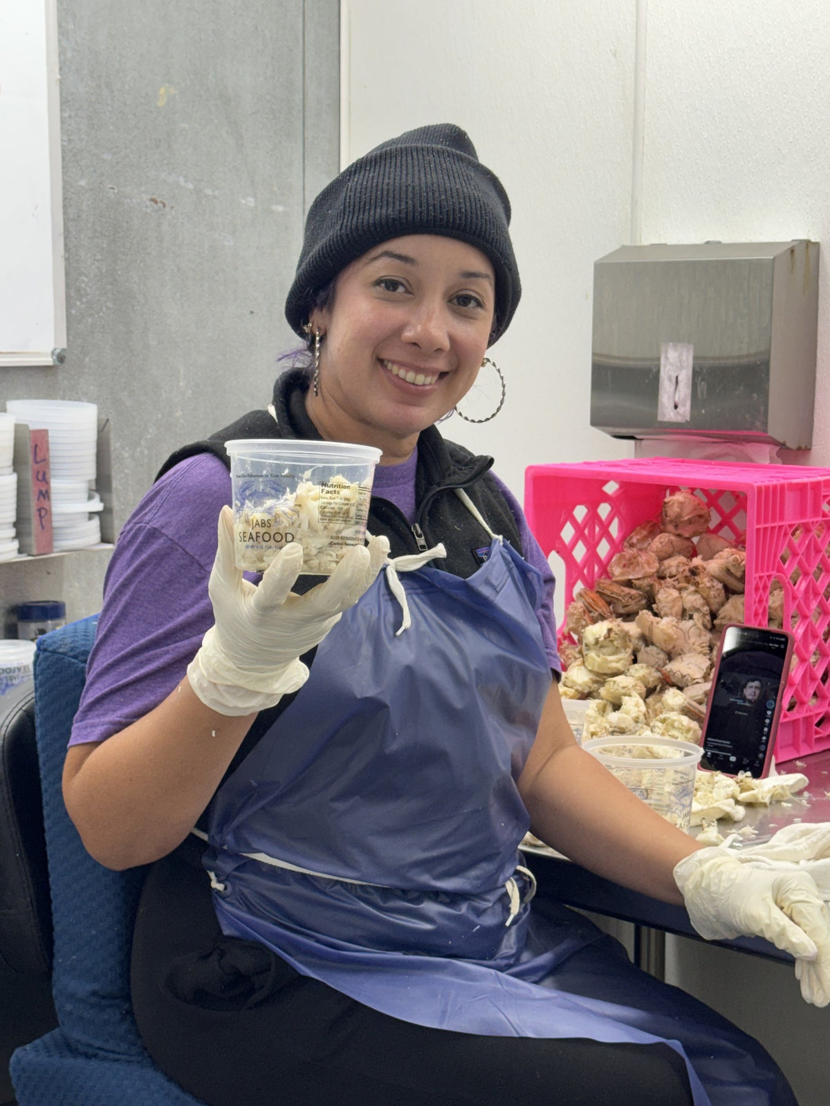 A Jab's Seafood crab picker holding a freshly filled tub of lump crab meat in the picking room